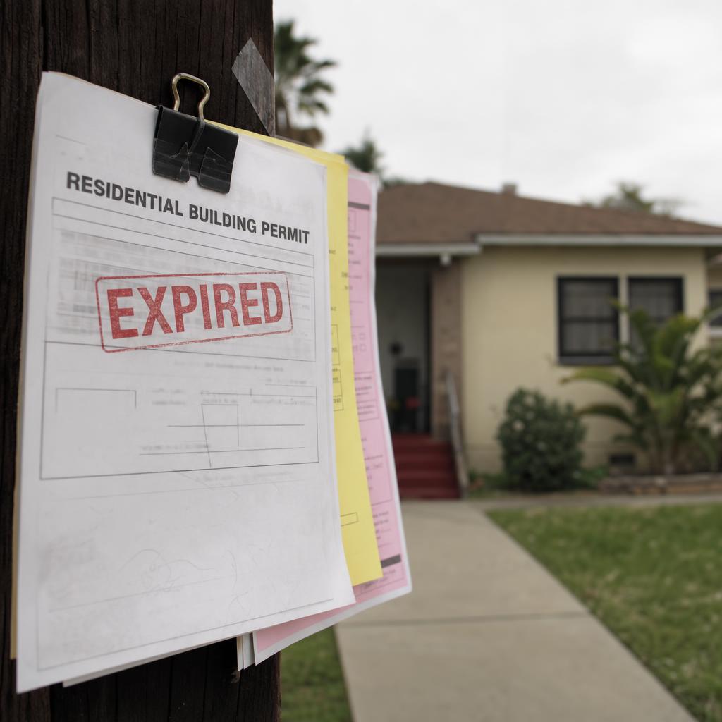 Contractor and inspector reviewing an old building permit on site in Los Angeles